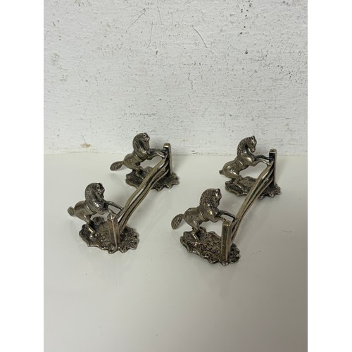 7 - A pair of silver plated knife rests each cast as horses at a three bar fence -