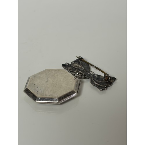 17 - An early 20th Century silver locket brooch, stamped silver, the tied ribbon surmount suspending an o... 