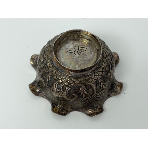 10 - An Indian white metal bowl, with wavy rim, decorated in the round with animals in a landscape -