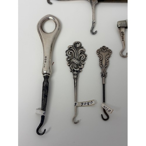 58 - A collection of glove hooks, to include two folding silver and mother-of-pearl examples, a Gorham st... 