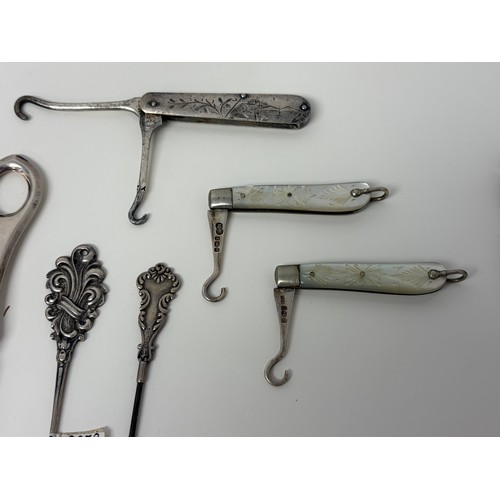 58 - A collection of glove hooks, to include two folding silver and mother-of-pearl examples, a Gorham st... 