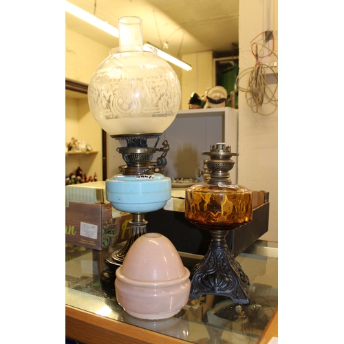 584 - Two oil lamps together with a single chimney and 2 shades.