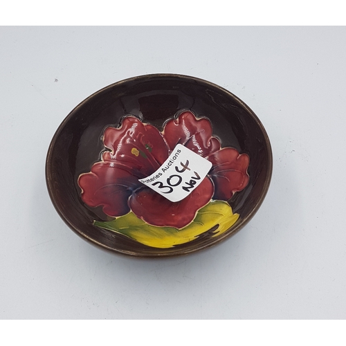 304 - Moorcroft Hibiscus pattern on brown ground small footed bowl, 11cm in diameter.