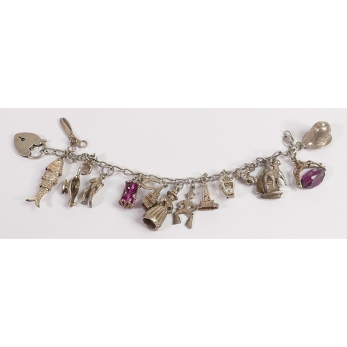 724 - Silver charm bracelet with 17 assorted charms, 64.4g.