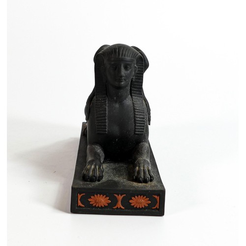 667 - Wedgwood black Basalt model of a Couchant Sphinx with terracotta Egyptian designs, h.10 x L16cm.