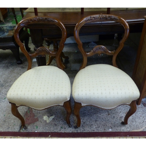 640 - A pair of carved Walnut balloon back upholstered bedroom chairs with brass castors to front supports