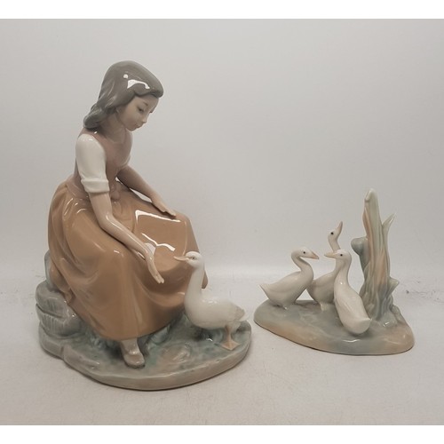 416 - Two Nao figures, one of a girl feeding a goose and one of a group of geese (2).