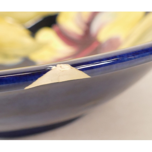 148 - Moorcroft Hibiscus on Blue Ground Shallow Footed Bowl, chip to rim, diameter 24.5cm