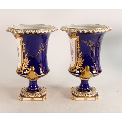 383 - A Pair of Royal Crown Derby hand painted twin handle urns. Painted with floral sprays by A. Gregory.... 