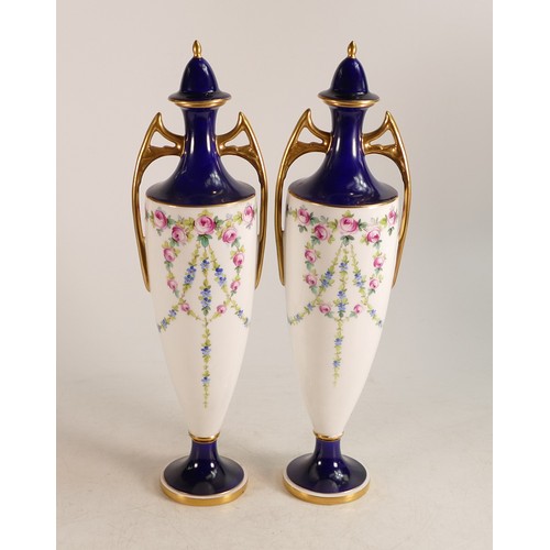 399 - A pair of Minton twin handled lidded vases decorated with pink roses, cobalt blue borders and gilt. ... 