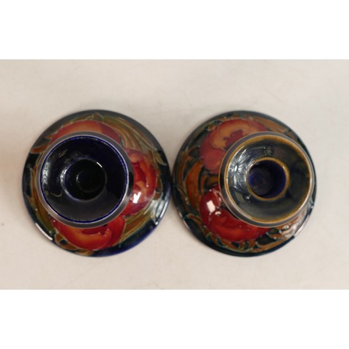 606 - Pair of William Moorcroft small candlesticks decorated in the Poppy design, h.10cm. (2)