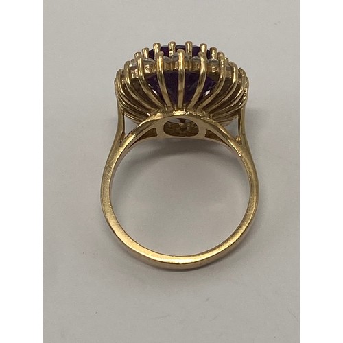 643 - 9ct gold ladies flamboyant dress ring, set with large oval amethyst stone surrounded by white stones... 