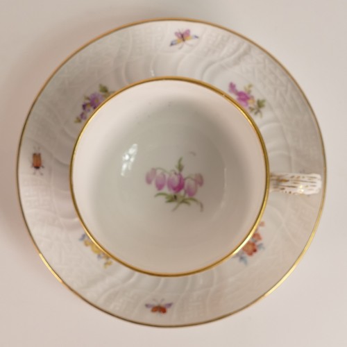 103 - Meissen, porcelain tea cup and saucer. Painted with floral and insect motifs on blanc white moulded ... 