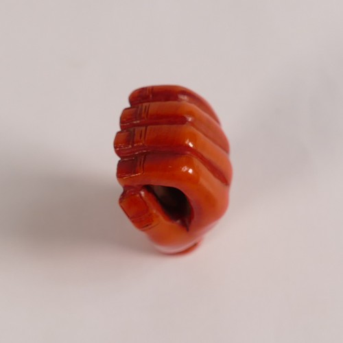 1110 - Japanese Coral Netsuke, in the form of dressed monkey in a large hand. Signed to base with two loop ... 