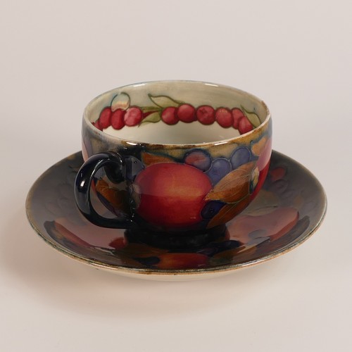 1260 - William Moorcroft tea cup and saucer in the Pomegranate design, cup decorated inside on cream ground... 