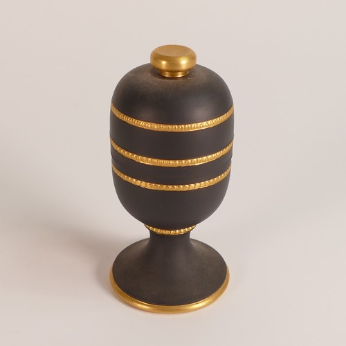 1401 - Wedgwood gold on black lidded footed jar. Decorated in 22ct gold with engine turned knurling techniq... 