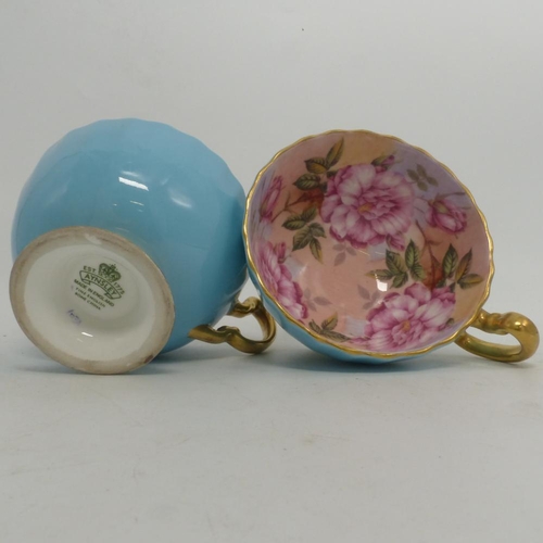 338 - Aynsley, Two Blue Ground Gilt Teacups with full internal image of roses. (2)