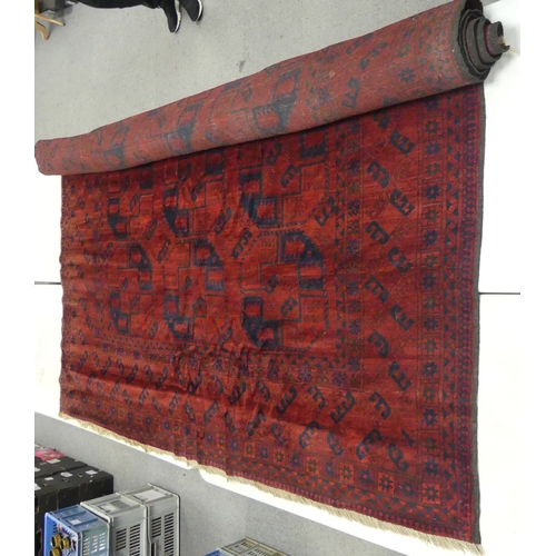 654 - Vintage Afghan tribal wool rug with a deep red field and navy blue accents, featuring a repeating oc... 