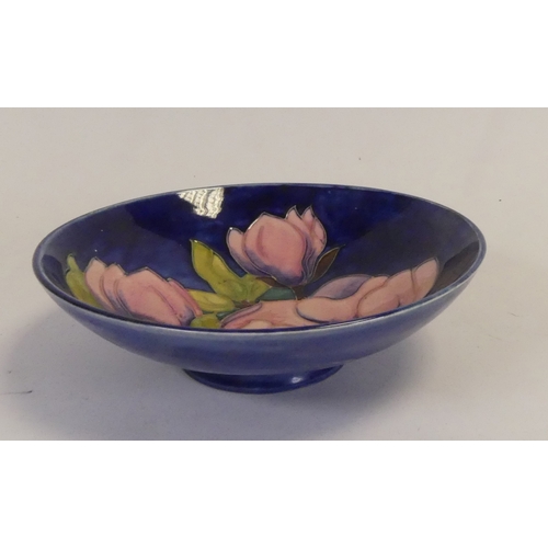 92 - Moorcroft footed bowl in the pink magnolia pattern on cobalt blue ground. (D: 18cm)