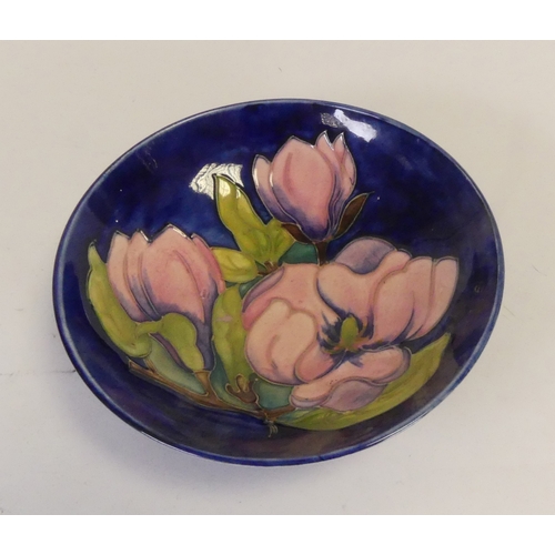 92 - Moorcroft footed bowl in the pink magnolia pattern on cobalt blue ground. (D: 18cm)