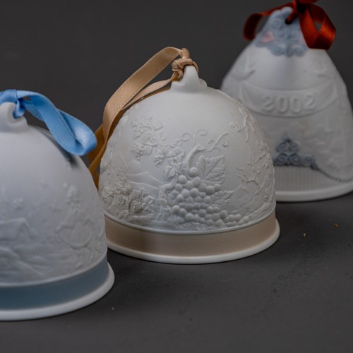A group of five Lladro bells with ribbons, various embossed deigns ...