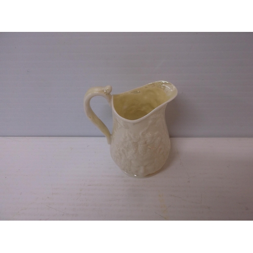 396 - A 3rd period Belleek jug with mask motif 11cmH