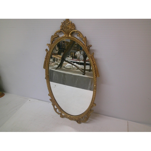 121 - An oval gilt metal framed mirror - 51cm x 28cm