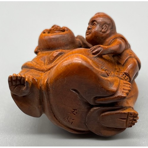 60 - Japanese hand carved netsuke; Laughing Buddha and child. Signed to the base. [3.5cm high]