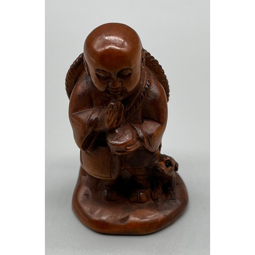 80 - Japanese hand carved netsuke; Praying figure with dog at his foot. Signed to the base. [5cm high]