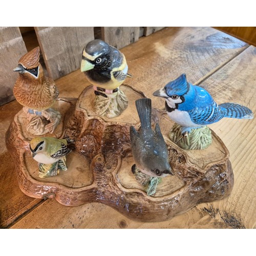 417 - Beswick and Royal Doulton tree stump stand with various Beswick bird figures.