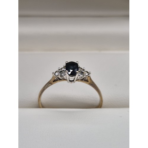 82 - 9ct yellow gold ladies ring set with an oval cut sapphire gem stone off set with three round cut dia... 