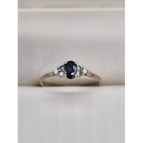 82 - 9ct yellow gold ladies ring set with an oval cut sapphire gem stone off set with three round cut dia... 