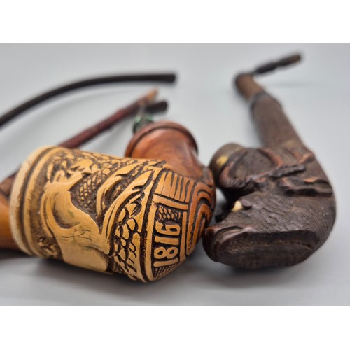 A collection of four antique pipes; Black forest carved stag smoking pipe,  devil style head smoking