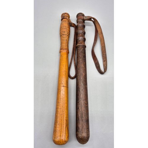 295 - Two antique oak wooden truncheons with leather straps.