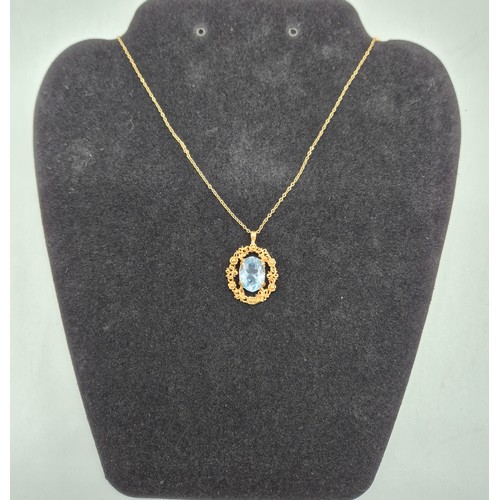 84 - 9ct yellow gold ornate pendant fitted with a blue aquamarine gem stone and a 9ct yellow gold chain. ... 