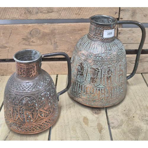 389 - Two antique Persian copper pourers/ jugs. Both worked with raised relief figures and panels. [Talles... 