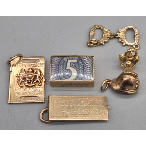 59 - Six various 9ct yellow gold charms; In Emergency Break Glass- contains bank note, British passport, ... 