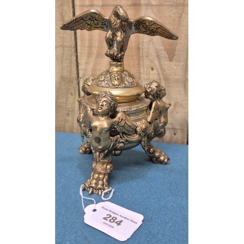 284 - Antique heavy brass ink well pot; Lid designed with an eagle finial. Body detailed with three cherub... 