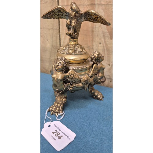 284 - Antique heavy brass ink well pot; Lid designed with an eagle finial. Body detailed with three cherub... 