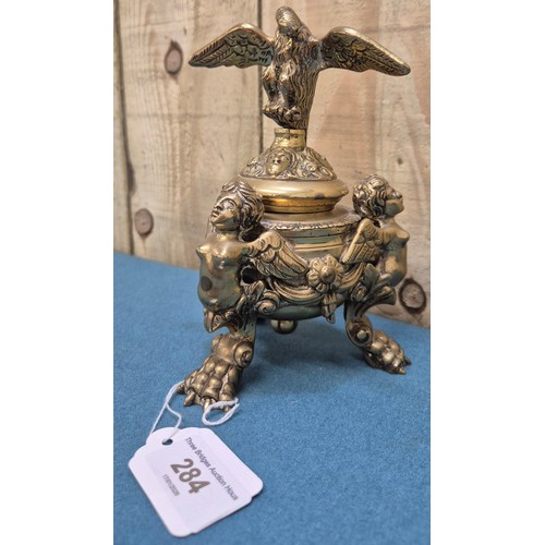 284 - Antique heavy brass ink well pot; Lid designed with an eagle finial. Body detailed with three cherub... 