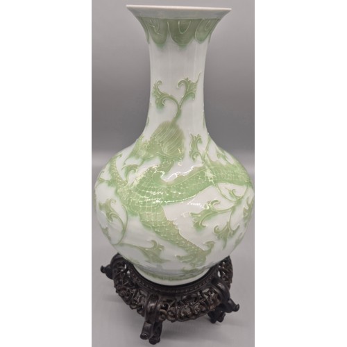 173 - Antique Chinese raised relief dragon pattern vase with reign mark to base on a wood carved stand.