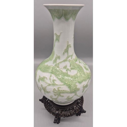 173 - Antique Chinese raised relief dragon pattern vase with reign mark to base on a wood carved stand.