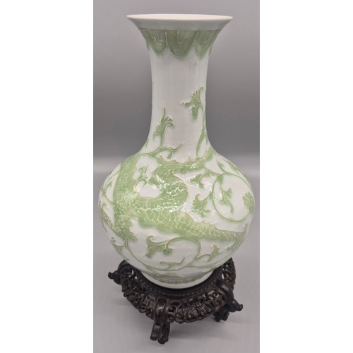 173 - Antique Chinese raised relief dragon pattern vase with reign mark to base on a wood carved stand.