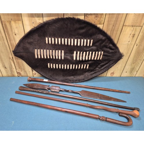 243 - Selection of African carved items; four African hand carved walking sticks, Zulu style shield and ca... 
