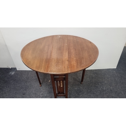 104 - Walnut-finish oval drop-leaf occasional table on castors H:68cm x W:84cm x D:69cm.