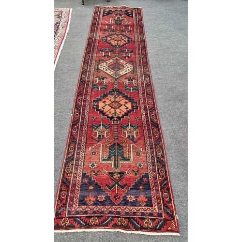 34 - Large and woven Persian  Heriz runner medallion design , L:404cm X W: 90cm.