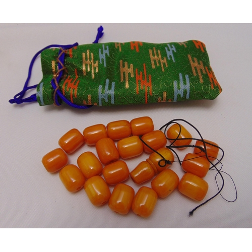 331 - A quantity of loose butterscotch amber beads in green silk pouch