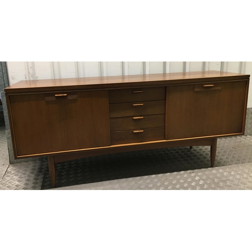 13 - A mid 20th century rectangular teak sideboard with hinged cupboards and drawers on four tapering cyl... 