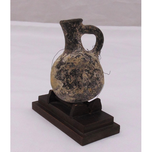 235 - A Roman miniature ewer mounted on a rectangular plinth, 10 cm (h)