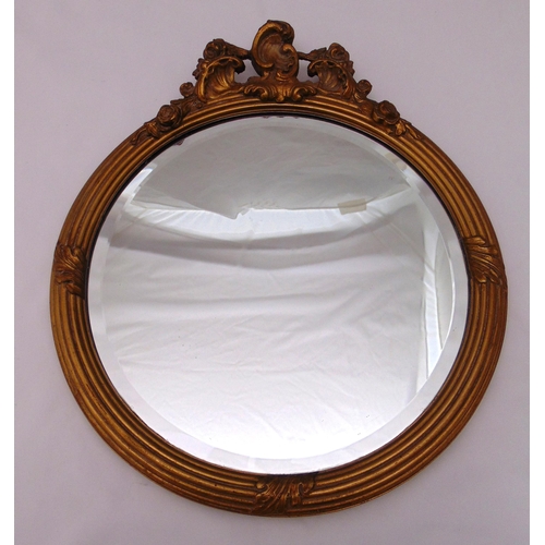 29 - A gilded wooden circular wall mirror surmounted by stylised leaves, 46.5 x 40cm